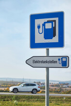 Electric Vehicle Charging Station Sign With Car Passing In Background