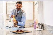 Smiling Male Chef With Pepper Grinder At Kitchen Counter