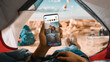 © Gorodenkoff - POV of a Tourist Vertically Holding a Smartphone and Checking Social Network Feed, Friends Latest Photos. Traveller Resting in a Tent on Top of a Rocky Mountain and Flying Hot Air Balloons