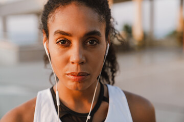 Wall Mural - Black sportswoman listening music while working out on parking