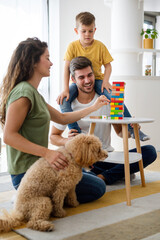 Wall Mural - Happy family having fun time, playing together at home with dog