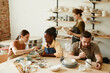 © Seventyfour - Warm toned portrait of diverse group of people enjoying pottery workshop in cozy studio