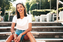 Portrait Of Young Beautiful Smiling Hipster Woman In Trendy Summer Jeans Shorts. Sexy Carefree Model Posing On The Street Background At Sunset. Positive Model Outdoors In Sunglasses