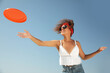 © New Africa - Happy African American woman throwing flying disk against blue sky on sunny day
