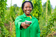 Shot Of A Female African Farmer In Nigeria Stretching Some Money Forward