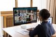 © fizkes - Rear back view focused serious millennial Indian businesswoman looking at computer monitor, discussing marketing research results report with colleagues by web camera video call conversation.