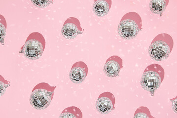 Christmas and New Year creative layout with disco ball decoration on pastel pink background. 80s or 90s aesthetic fashion holiday concept. Minimal holiday idea.