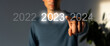 Finger pressing blue start 2023 button on virtual interface on gray background with copy space for text. Concept of new year. Businessman pressing 2023 start up business. Beginning of New Year 2023