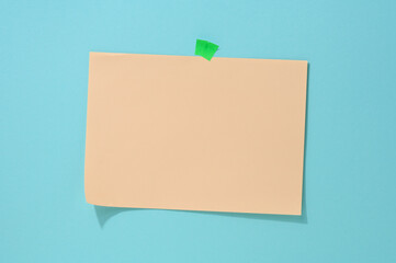 Wall Mural - blank rectangular beige sheet of paper glued on a light blue background. Place for an inscription, announcement