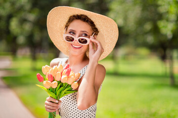 Poster - Photo of young happy joyful positive woman dream lady summer sun hold hands tulips wear glasses outside outdoors park