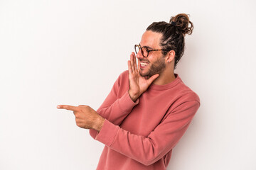 Young caucasian man isolated on white background saying a gossip, pointing to side reporting something.