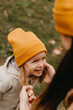 © Ananass - Young happy and smiling mom with her little daughter in arms hugging and kissing spending a weekend on a walk in autumn park. selective focus, noise effect, Autumnal mood