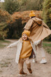 © Ananass - Young happy and smiling mom with her little daughter in arms hugging and kissing spending a weekend on a walk in autumn park. selective focus, noise effect, Autumnal mood