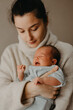 © Ananass - Loving mother carying of her newborn baby at home. Bright portrait of happy mum holding cute infant child on hands. Mother hugging her little 1 months old daughter.