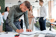 © alfa27 - Young confident business man signing financial contract, put write signature on legal corporate paper fill document form buy insurance loan, making business agreement, colleagues in the background
