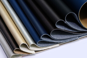 Samples of leatherette in different shades top view. Artificial leather color palette catalog. Eco leather in blue, black, white, background. Dark shades leather swatches background.