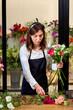Process of making a bouquet of seasonal blooming flowers. Female florist making bouquet in flower shop, at work place. confident caucasian lady in apron enjoy doing handmade bouquet