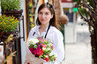 Startup successful sme small business entrepreneur owner charming woman standing with flowers at florist shop outdoors. Portrait of nice caucasian lady, successful flower business owner posing
