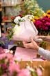people, shopping, sale, floristry and consumerism concept. close-up female hands giving flowers to customer at flower shop. beautifully made prepared bouquet on women's day or another holiday