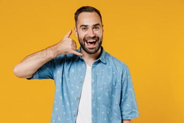 Wall Mural - Young smiling happy cheerful consultant caucasian man 20s wearing blue shirt doing phone gesture like says call me back isolated on plain yellow background studio portrait. People lifestyle concept.