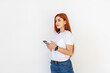 © dianagrytsku - Pleased smiling red haired woman holds cell phone over white background