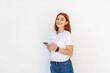 © dianagrytsku - Portrait of a smiling redhead woman holding phone and texting over white background