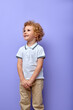 caucasian sweet child boy looking empty space smiling isolated on yellow color background, male kid is dressed casually in t-shirt, have fun, enjoying spare time, looking up, having curly hair