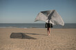 © Milou Dirks - abstract portrait of girl on beach near ocean shore waving silver fabric