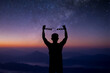 Young man standing alone on top of the mountain with beautiful night sky, star and Milky Way and open both arms with chains on his arms. He felt free from the shackles tied to his arms.