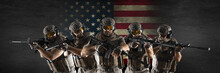 Professional Special Forces Soldiers, During A Special Operation Against A Dark Concrete Wall And US Flag Background. They Are Defending Flag. Photo Format 3x1.