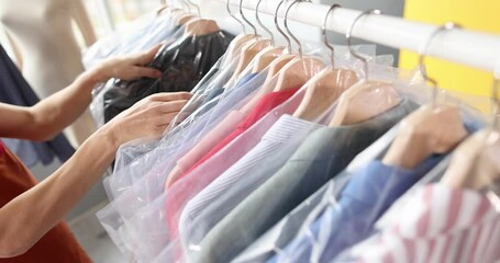 Wall Mural - Woman seamstress going through clothes in plastic bags on hanger in atelier 4k movie