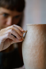 Poster - Decorating pottery: young woman ceramics master shaping potter jug while art class in handicraft studio. Closeup of focused craftswoman creating pot in workshop. Handcraft hobby and leisure recreation