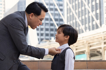 Asian business father and son confidence child want to be like a his dad parent and young boy standing in city with cityscape background Planning in future life. 