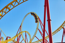 Roller Coaster In An Amusement Park Against The Blue Sky. The Concept Of Attractions And Extreme Recreation