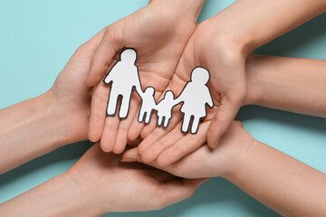 Wall Mural - People holding paper family cutout on light blue background, top view