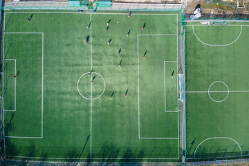 Aerial view of soccer players playing football on green sports stadium