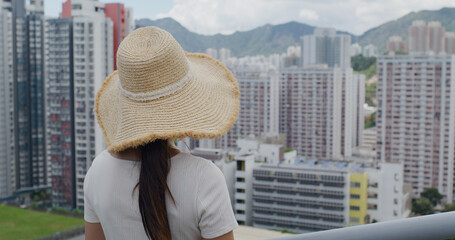 Wall Mural - Woman wear straw hat and look at the city of Hong Kong