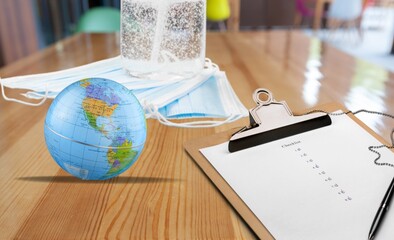 Poster - Medical and healthcare concept. Facemask, hand sanitizer, earth globe and paper on the desk