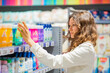 © wifesun - beautiful young woman in a white coat takes shampoo from the shelf in the supermarket