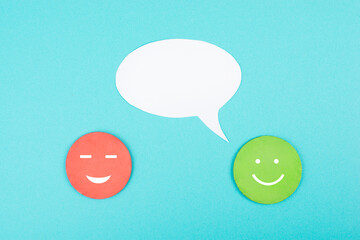Wall Mural - Smiling faces with a speech bubble, blue colored background, copy space, rating, positive feedback, customer experience