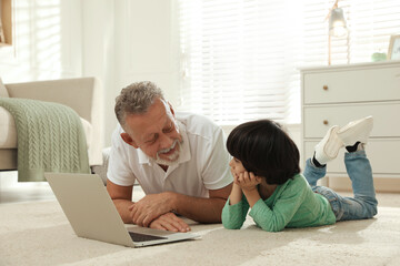 Wall Mural - Grandfather and his grandson using laptop together on floor at home