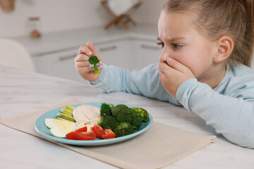 Canvas Print - Cute little girl covering mouth and refusing to eat dinner in kitchen