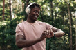 © Shopping King Louie - Male runner, American man checking fitness progress on his smartwatch while walking in the woods in nature