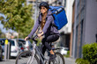 delivery woman riding electric bicycle in city