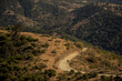 © Carlos - people in the distance hiking in a dirt road between the hills