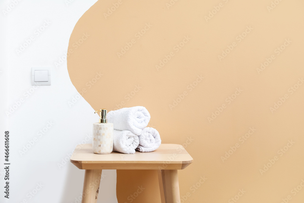 Table with towels and cosmetic bottle near color wall