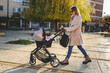 Side view full length of caucasian woman mother pushing stroller with baby in the city in autumn day motherhood concept