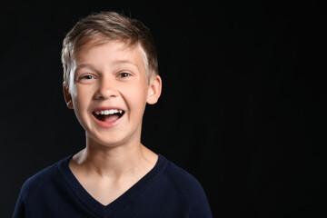 Portrait of happy little boy on black background