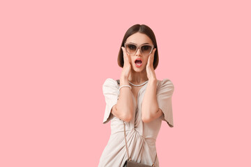 Poster - Shocked woman in stylish sunglasses and jewelry on color background