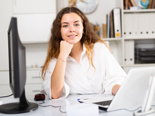 Wall Mural - Portrait of young elegant confident female office worker in a company at a modern workplace